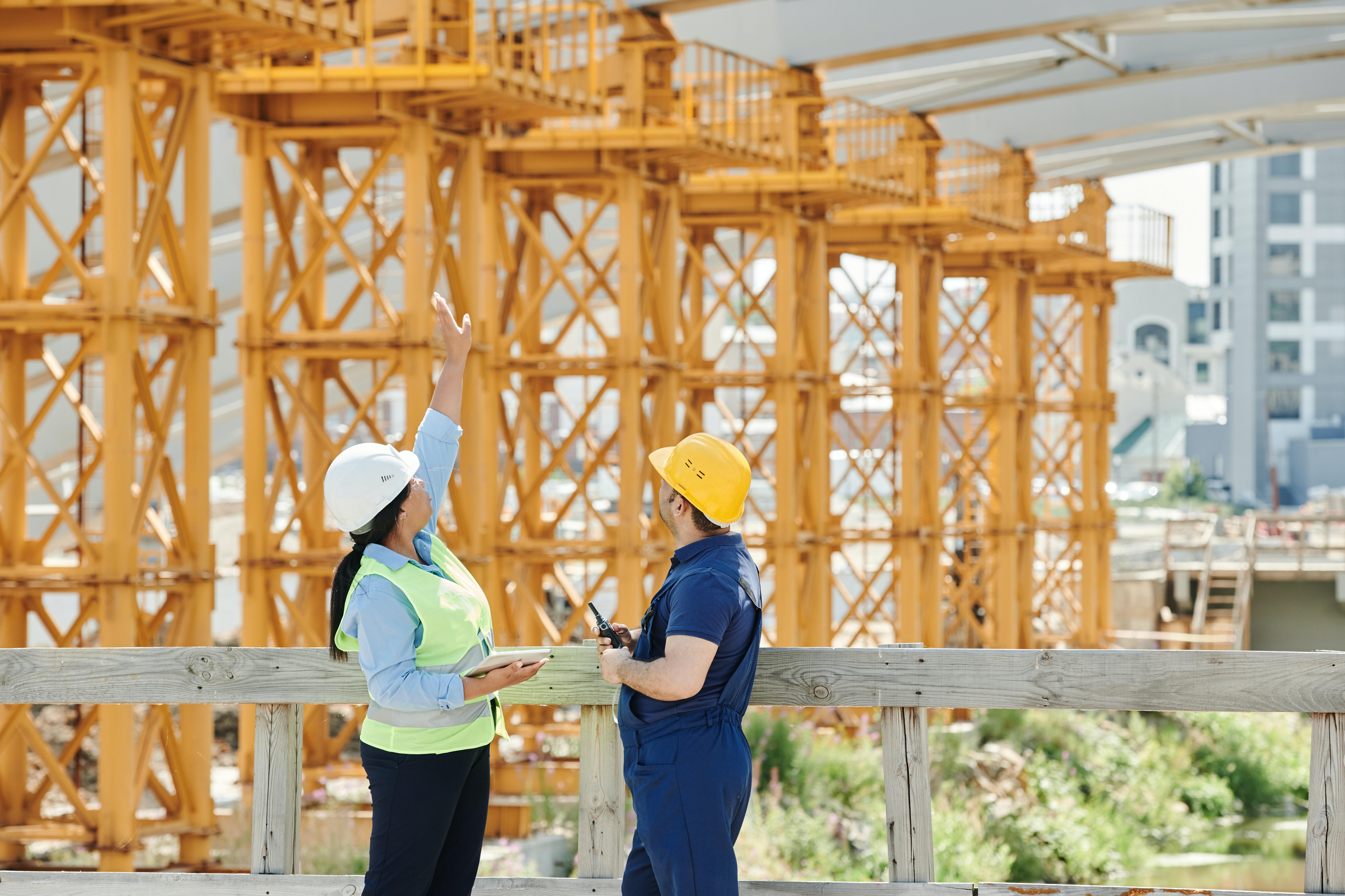 A Man and a Woman with PPE's Talking at a Construction Site
